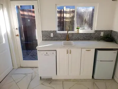 a white kitchen with a sink and a window at Garden View double room suite at Trout Lake in Vancouver