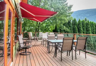 a deck with chairs and a table and an umbrella at Custom Built Home on the Beach in Nelson