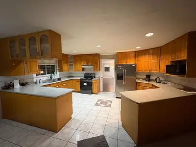 a large kitchen with wooden cabinets and stainless steel appliances at Delta Guest House - Scott Rd & Rapid Transit - Airport 20 Min - Free Parking & Fast Wi-Fi in Delta