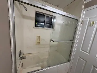 a shower with a glass door in a bathroom at Delta Guest House - Scott Rd & Rapid Transit - Airport 20 Min - Free Parking & Fast Wi-Fi in Delta