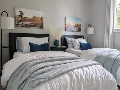 a bedroom with two beds with white sheets and blue pillows at Lakeview Hideaway in Victoria