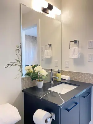 a bathroom with a sink and a large mirror at NEW Luxury Family Friendly Entire House Near Downtown WEM, 3 Bedrooms in Edmonton