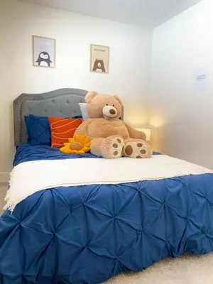 a teddy bear sitting on top of a bed at NEW Luxury Family Friendly Entire House Near Downtown WEM, 3 Bedrooms in Edmonton