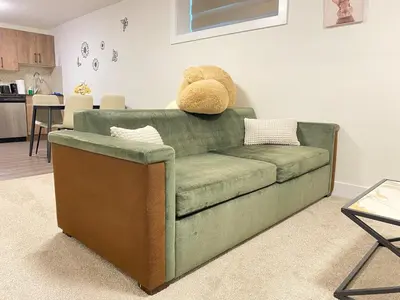 a teddy bear sitting on top of a green couch at Modern Cozy Entire Guest Suite in Central Edmonton in Edmonton