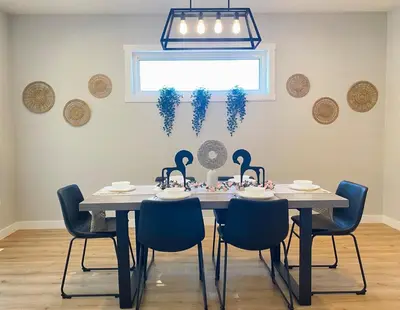 a dining room table with blue chairs and a chandelier at The Downtown Oasis - A Spacious Family Friendly 3 Bedroom House Close to Everything in Edmonton
