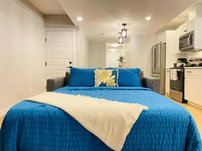 a blue bed in a room with a kitchen at The Private Central Edmonton Suite - Comfortable & Fully-Equipped Basement Suite in Edmonton