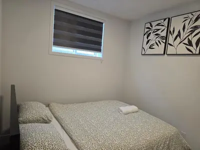 a white bedroom with a bed and a window at Cozy 2 Bedroom Apartment in Calgary