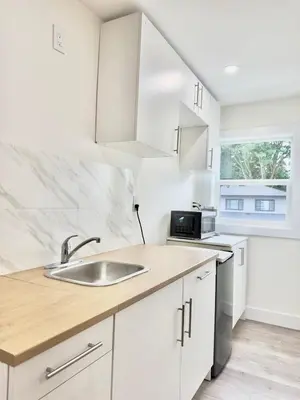 a kitchen with white cabinets and a sink at One-Bedroom Suite in Gibsons in Gibsons