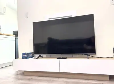 a large flat screen tv sitting on a white entertainment center at One-Bedroom Suite in Gibsons in Gibsons