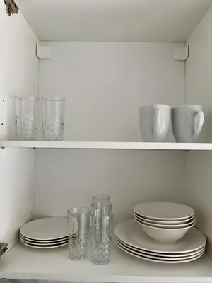 a shelf with plates and cups and glasses on it at One-Bedroom Suite in Gibsons in Gibsons