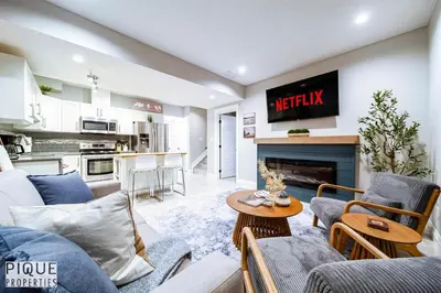 a living room with a couch and a tv on the wall at Chic Retreat with Hot Tub - King Bed - Fireplace - WEM in Edmonton