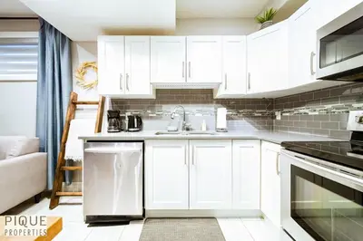 a kitchen with white cabinets and a sink at Chic Retreat with Hot Tub - King Bed - Fireplace - WEM in Edmonton
