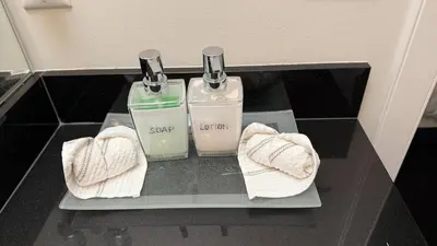 two bottles of soap and towels on a shelf at Carrie The Gentle Nest 1 in Coquitlam