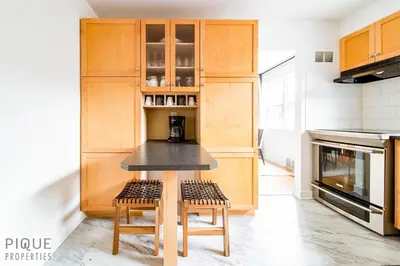 a kitchen with wooden cabinets and a table with stools at Nordic Spa Retreat - Hot Tub - King Bed - Firepit - BBQ in Edmonton