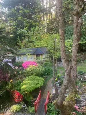 a garden with red benches and flowers in front of a house at Quiet Backyard Cabin in North Vancouver