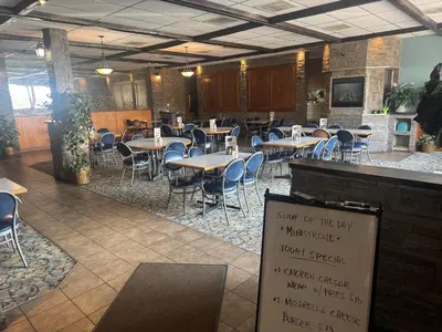 a restaurant with tables and chairs and a sign at Big Horn motor Inn in Grande Cache
