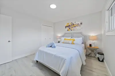 a white bedroom with a large white bed with yellow pillows at Bungalow Southgate University WEM Rogers Place Saville & Snow Resort in Edmonton
