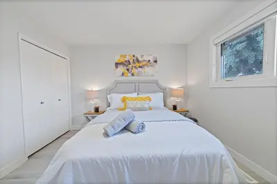 a white bedroom with a large bed with two towels on it at Bungalow Southgate University WEM Rogers Place Saville & Snow Resort in Edmonton