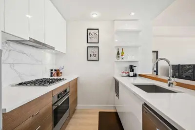 a white kitchen with a sink and a stove at Riverside Retreat - FREE Banff Pass, Gym, Parking! in Calgary