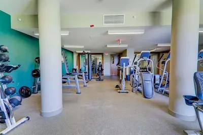 a gym with rows of exercise equipment and columns at Riverside Retreat - FREE Banff Pass, Gym, Parking! in Calgary