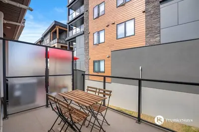 a patio with a table and chairs on a balcony at Executive Suite with King Bed Garage AC Free Banff Pass 65 Inch TV in Calgary
