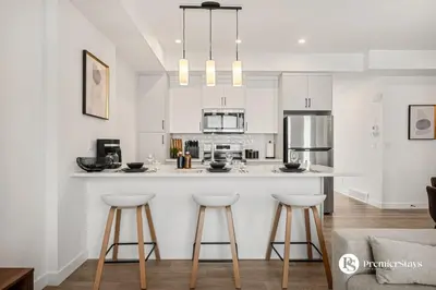 a kitchen with white cabinets and a counter with stools at Executive Suite with King Bed Garage AC Free Banff Pass 65 Inch TV in Calgary
