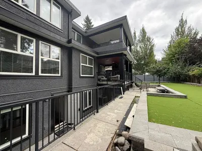 a black house with a green lawn in front of it at Private two bedroom basement suite Sleeps six people in Surrey