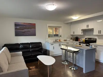 a living room with a couch and a kitchen at Private two bedroom basement suite Sleeps six people in Surrey