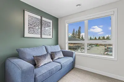 a living room with a blue couch and a window at Peak n Plunge Insane MTN View Pool n Hot Tub K201 in Canmore