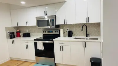 a kitchen with white cabinets and a sink and a microwave at Lucas in Edmonton