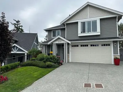 a gray house with a garage and a driveway at Modern One-Bedroom Retreat in Bear Mountain in Langford