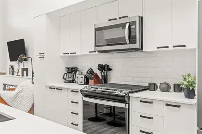 a kitchen with white cabinets and a microwave above a stove at 3BR Escape BBQ, Balcony, Near Banff & DT in Canmore