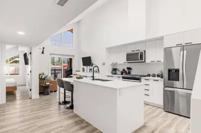 a white kitchen with a sink and a refrigerator at 3BR Escape BBQ, Balcony, Near Banff & DT in Canmore