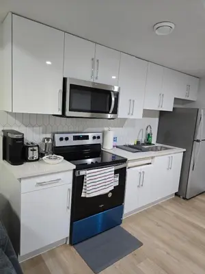 a kitchen with white cabinets and a black stove top oven at Lush 1 Bedroom house with WiFi in Edmonton in Edmonton