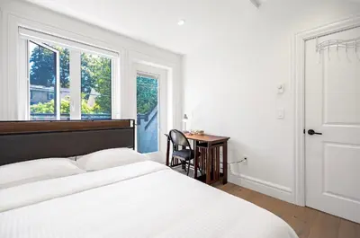 a bedroom with a bed and a desk and a window at Dunbar Brand-new laneway house in Vancouver