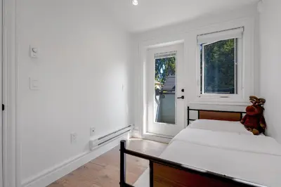 a white bedroom with a teddy bear sitting on a bed at Dunbar Brand-new laneway house in Vancouver