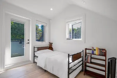 a bedroom with a bed and two windows at Dunbar Brand-new laneway house in Vancouver