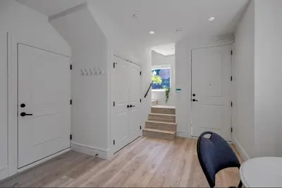 a hallway with white doors and a table and a chair at Dunbar Brand-new laneway house in Vancouver