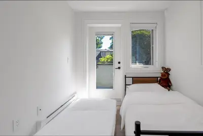 three beds in a room with two windows at Dunbar Brand-new laneway house in Vancouver
