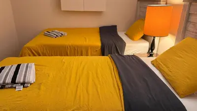 two beds in a room with yellow and gray sheets at Calgary Super Cozy Guest Rooms Near Banff in Calgary