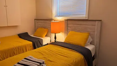 a room with two beds with yellow pillows at Calgary Super Cozy Guest Rooms Near Banff in Calgary