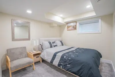 a bedroom with a bed and a chair and a window at Anna Suite Rental in Edmonton