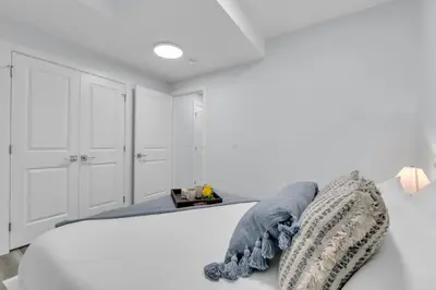a white bedroom with a bed and white cabinets at Basement in Calgary - 10 Mins from Calgary Airport in Calgary