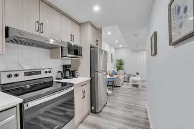 a kitchen with stainless steel appliances and a living room at Basement in Calgary - 10 Mins from Calgary Airport in Calgary