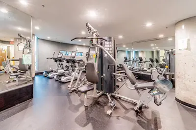 a gym with several tread machines in a room at Cozy Urban Living! 2 mins from BC place, private parking ! in Vancouver