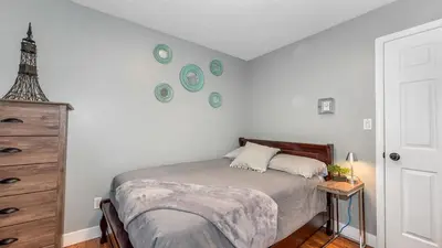 a bedroom with a bed and a dresser and plates on the wall at Knockan Hill Rentals - Ground Floor Suite in Victoria