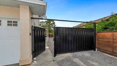 a black garage door with a wooden gate at Knockan Hill Rentals - Ground Floor Suite in Victoria