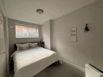 a bedroom with a white bed and a window at Cowichan Valley Retreat with Sauna & Free EV Charger in Duncan