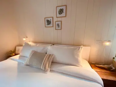 a bed with white sheets and pillows in a room at Fern's Edge in Port Renfrew