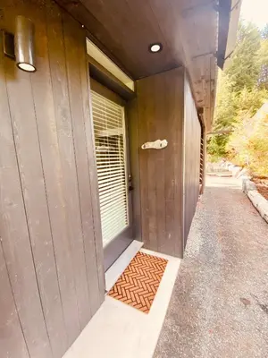 a hallway of a building with a door and a mat at Fern's Edge in Port Renfrew